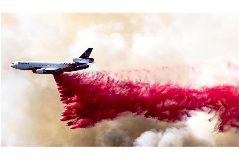 Ein Flugzeug wirft am 11. Januar 2025 eine rote Feuerlöschflüssigkeit aus Phos-Chek-Löschmittel in den Mandeville Canyon bei Los Angeles ab.