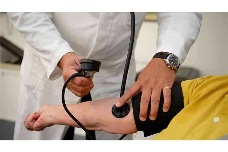 Ein Hausarzt misst in seiner Praxis in Stuttgart einer Patientin den Blutdruck.