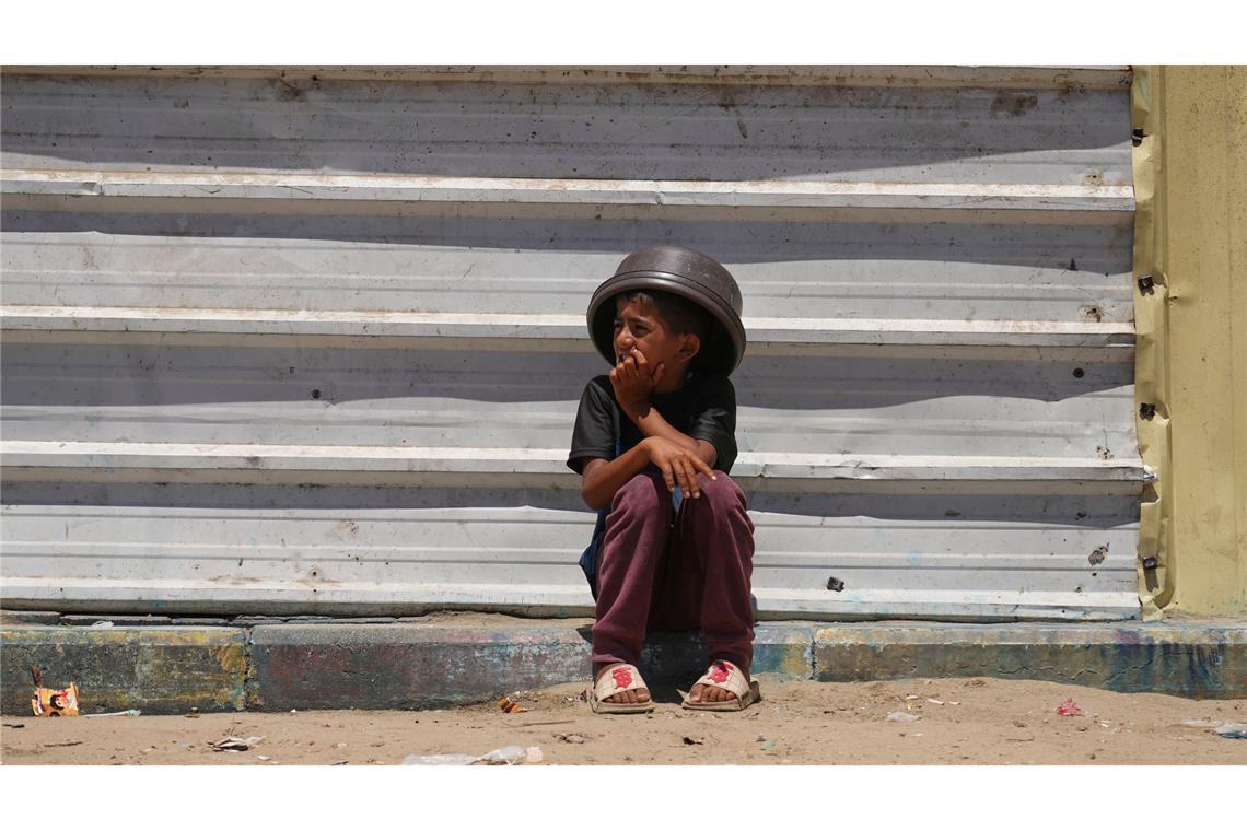 Bilder des Tages Ein Junge sitzt in der Nähe einer Lebensmittelverteilungsküche im südlichen Gazastreifen auf einem Bordstein.