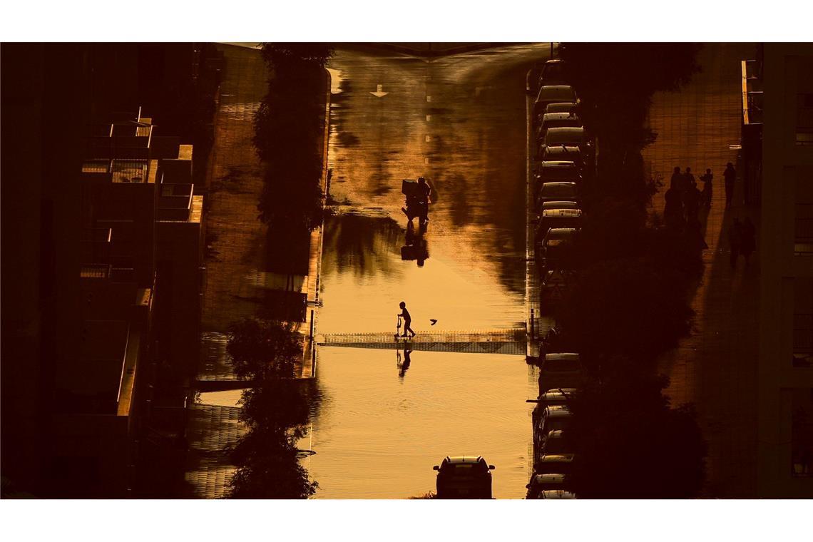 Ein Junge überquert eine mit Regenwasser gefüllte Straße in Schardscha, Vereinigte Arabische Emirate.