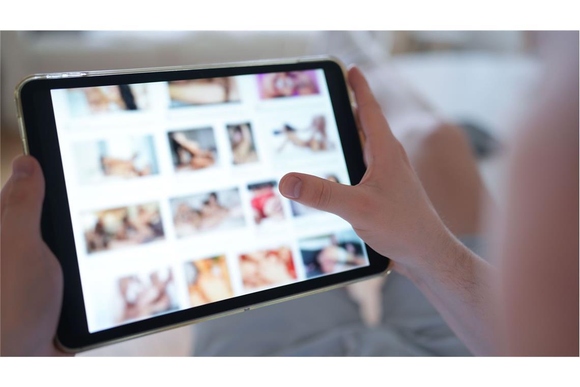 Ein junger Mann schaut sich auf einem Smartphone eine Porno-Internetseite an (gestellte Szene).