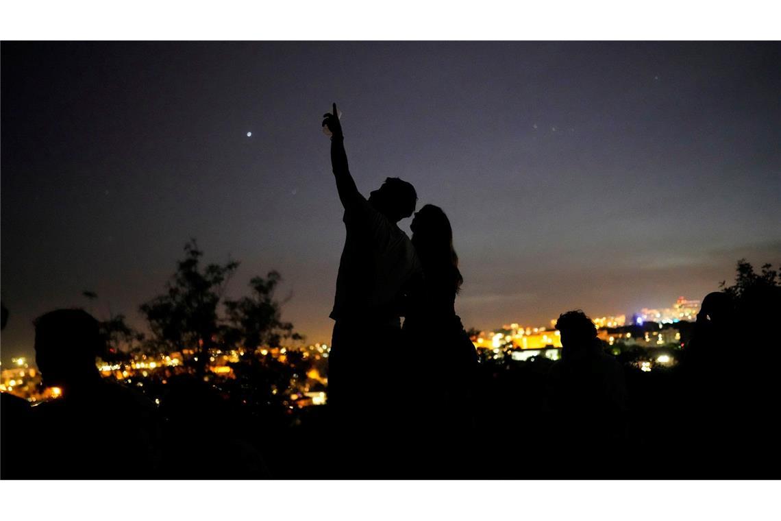 Ein junges Paar steht auf einer Mauer und betrachtet den Himmel an einem Aussichtspunkt über Lissabon während eines landesweiten Stromausfalls.