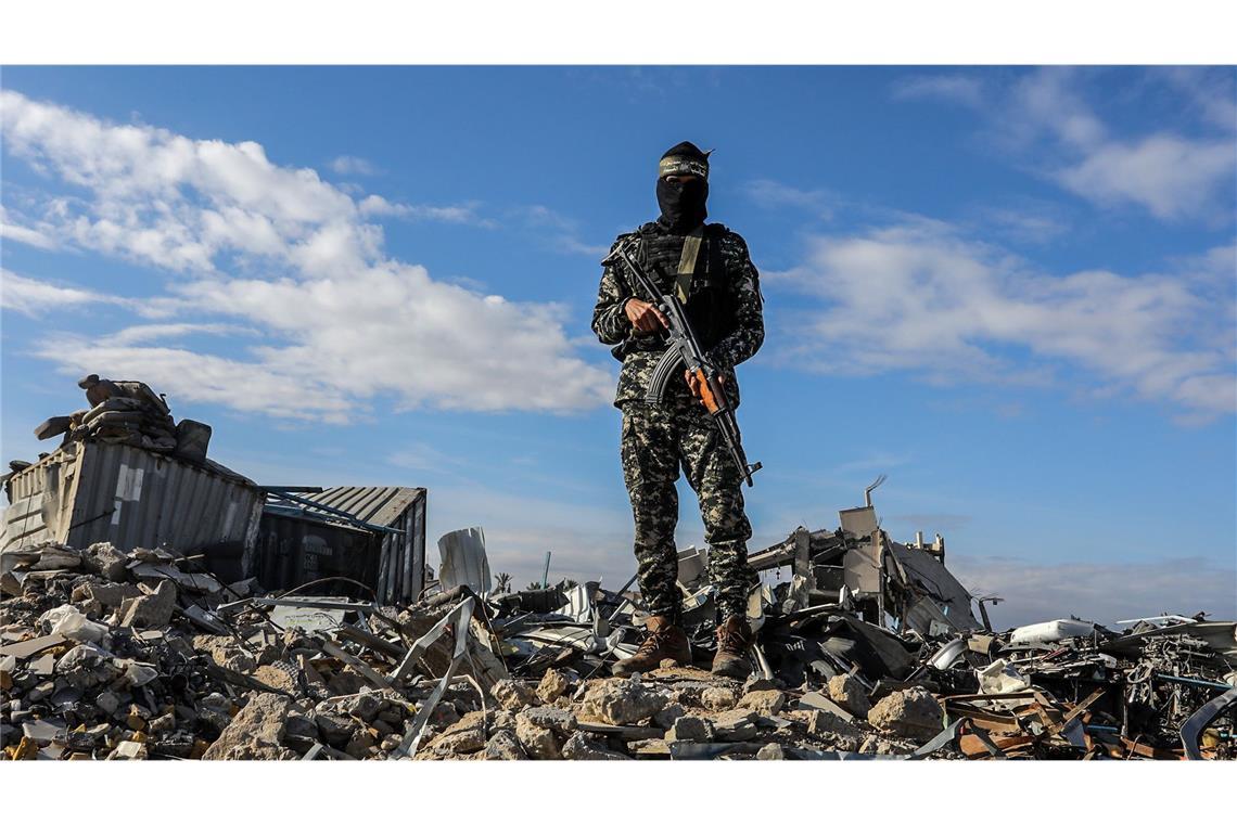 Deutsch-Israeli unter drei am Samstag freizulassenden Geiseln Ein Kämpfer der Al-Kassam-Brigaden, des militärischen Flügels der Hamas, steht in der Nähe von Ruinen Wache, während israelische Geiseln an Vertreter des Internationalen Komitees vom Roten Kreuz (IKRK) übergeben werden. (Archivbild)