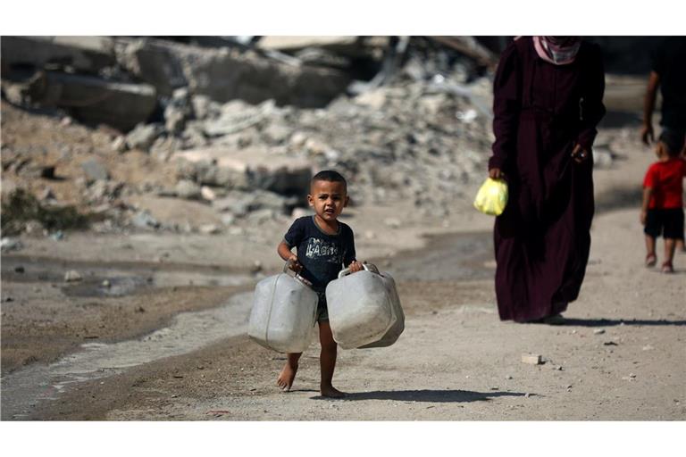 Ein Kind trägt Kanister, während Palästinenser versuchen, ihren täglichen Wasserbedarf zu decken, indem sie Kanister aus Wassertankwagen füllen, die in das Gebiet in Gaza-Stadt gebracht wurden.