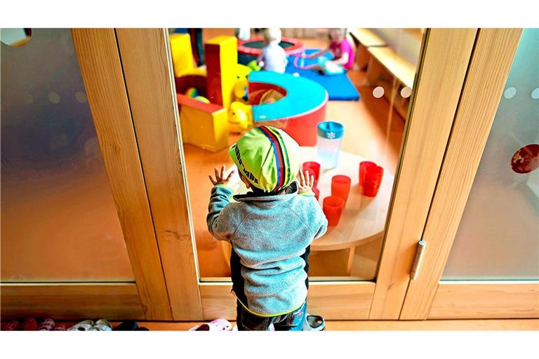 Ein Kleinkind steht an einer Glasscheibe in einer Kindertagesstätte. (Archivbild).