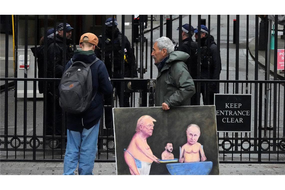 Streit um Krim: Trump geht Selenskyj an, USA erhöhen Druck Ein Künstler geht in London mit einem Gemälde von Trump, Selenskyj und Putin am Tag der Ukraine-Gespräche vor den Toren der Downing Street 10 entlang.