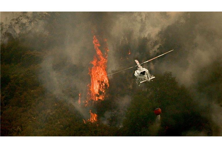 Ein Löschhubschrauber wirft Wasser über einem Feuer in der spanischen Provinz Ourense ab.