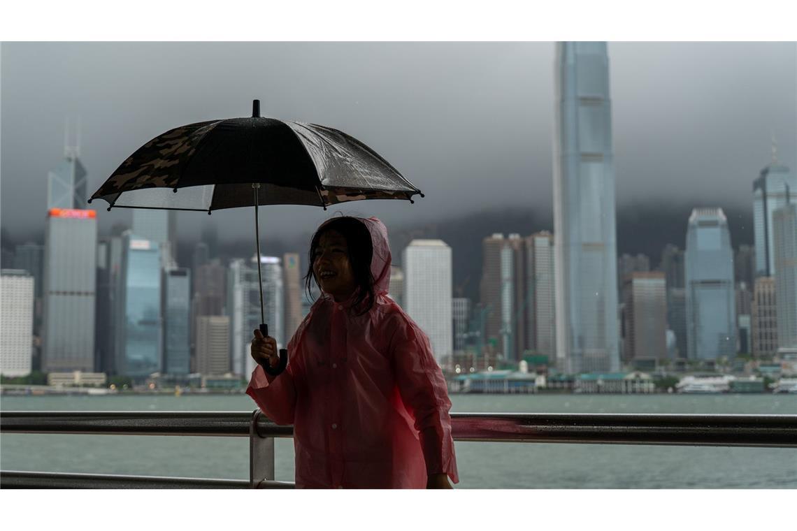 Bilder des Tages Ein Mädchen hält einen Regenschirm in Tsim Sha Tusi vor dem Victoria Harbor und der Skyline von Hongkong während des Taifuns "Tapah".