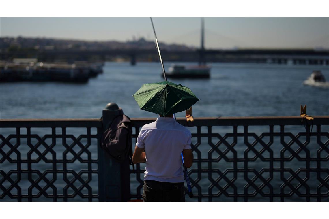 Ein Mann angelt an einem heißen Sommertag auf der Galata-Brücke in Istanbul.