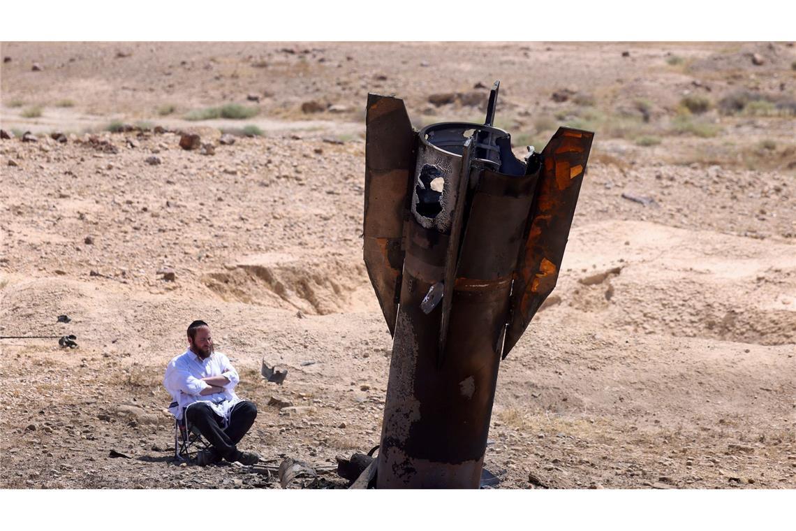 Ein Mann betrachtet das Wrack einer Rakete, die nach einem iranischen Angriff im Westjordanland aus dem Boden ragt.
