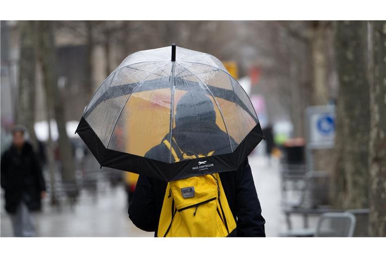 Ein Mann mit Regenschirm geht durch die Stadt (Symbolfoto).