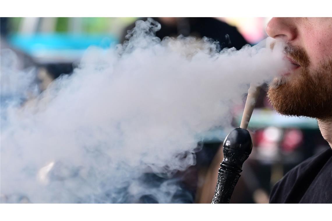 Ein Mann raucht in einer Shisha-Bar eine Wasserpfeife.