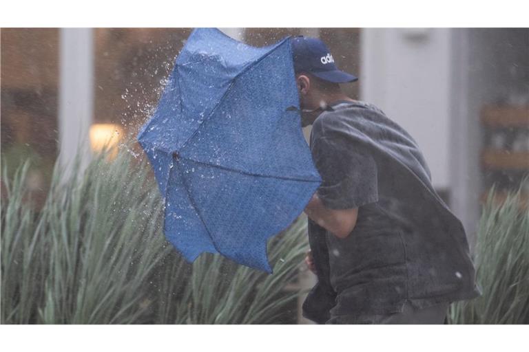 Ein Mann rennt in Stuttgart durch starken Regen und versucht, sich mit einem Regenschirm zu schützen. (zu dpa: «Regnerischer Tag: Wo sogar Gewitter und Sturmböen drohen»)