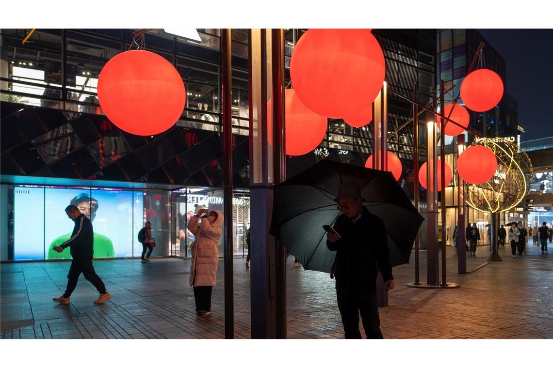 Bilder des Tages Ein Mann schaut auf sein Telefon in der Nähe von roten Zierkugeln am Taikoo Li Sanlitun Einkaufszentrum in Peking.