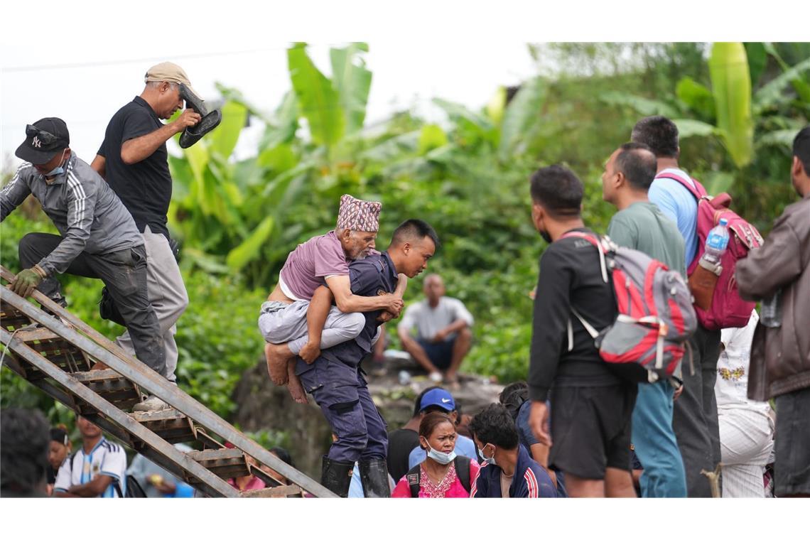 Ein Mann wird im Katastrophengebiet in Nepal von einem Polizisten auf dem Rücken getragen.