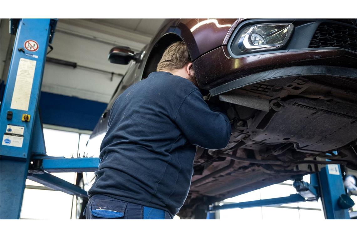 Autoreparatur-Studie: Neue Ersatzteile schlecht fürs Klima Ein Mechaniker schaut in einer Kfz-Werkstatt in den Radkasten eines Autos.