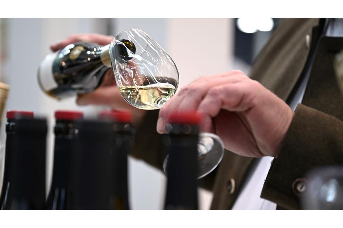 Ein Mitarbeiter des badischen Weinguts Bimmerle gießt am Prowein-Messe-Stand seiner Firma Riesling in ein Glas.
