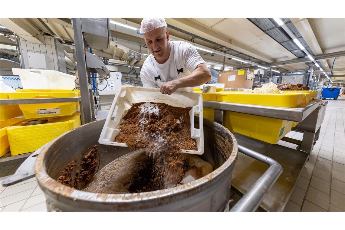 Ein Mitarbeiter des Lebkuchenherstellers Schmidt kippt in der Produktion verschiedene Rohstoffe zur Herstellung von Lebkuchenmasse in einen Behälter.