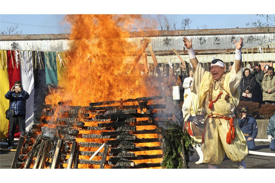 Ein Mönch wirft Glücksbringer und Amulette als Dank in ein Feuer.