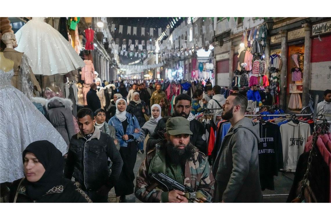 Bilder des Tages Ein Oppositionskämpfer geht zwischen Kunden in Damaskus über den Markt