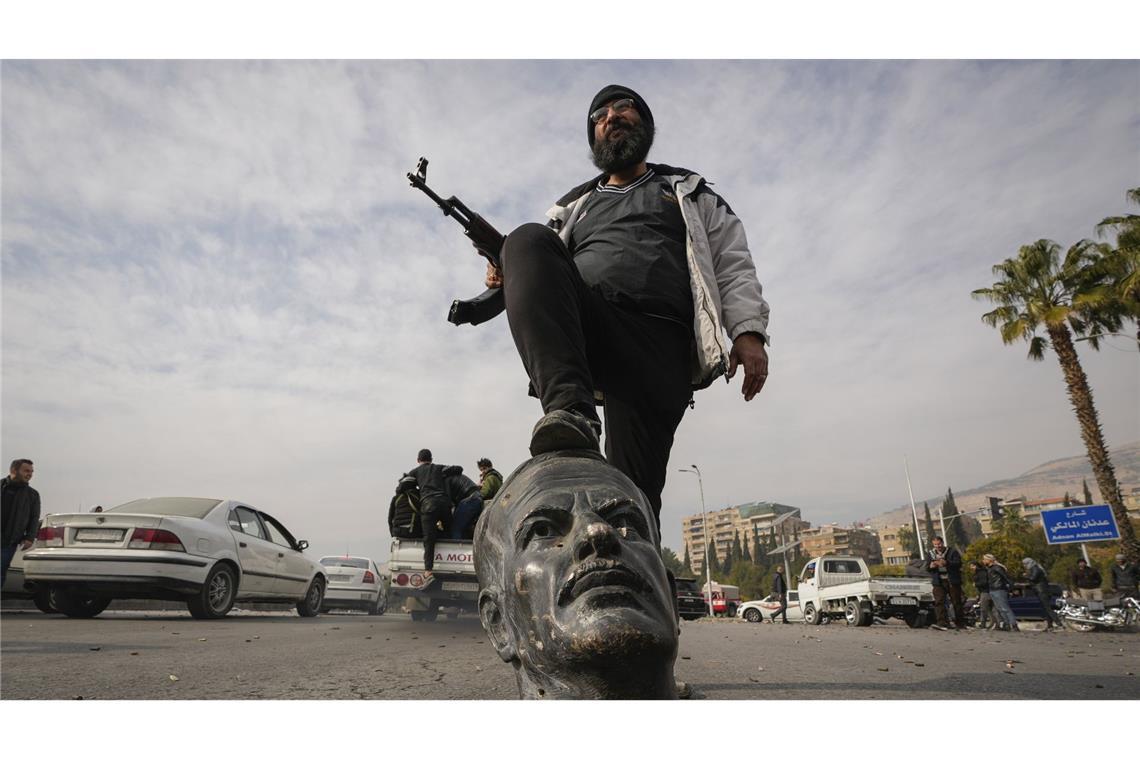 Bewaffnete Gruppen sagen in Abkommen Auflösung zu Ein Oppositionskämpfer tritt auf den abgetrennten Kopf einer Statue des verstorbenen syrischen Präsidenten Hafis al-Assad. Die neuen Machthaber in Syrien haben sich mit „allen bewaffneten Gruppen“ auf deren Auflösung geeinigt (Archivfoto).