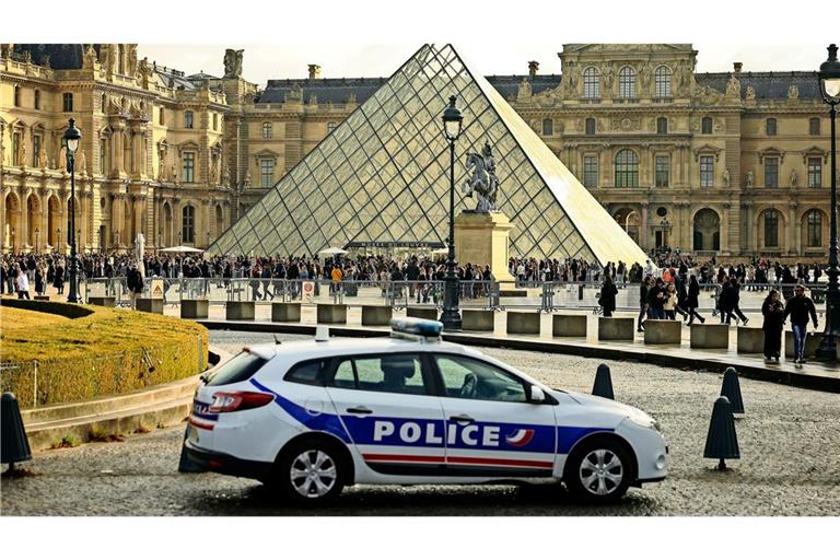 Ein Polizeiauto parkt im Hof des Louvre während Besucher vor der Glaspyramide in einer Schlange stehen. (Symbolbild)