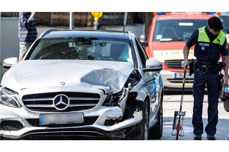 Ein Polizist sichert nach einem Unfall zwischen einem Auto und einem Bus die Spuren am Unfallort.