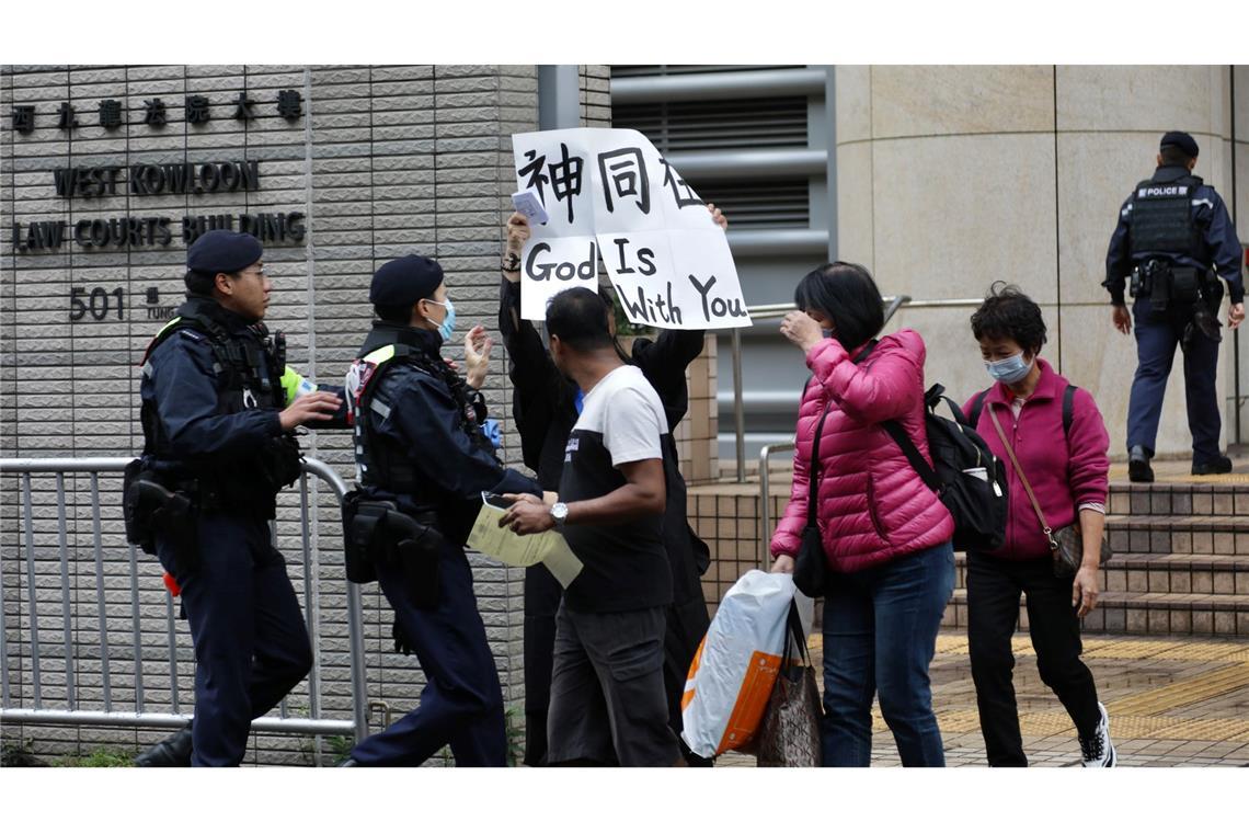 Bilder des Tages Ein Polizist versucht, eine Frau daran zu hindern, vor dem Gericht in West Kowloon ein Transparent mit der Aufschrift "Gott ist mit dir" in englischer und chinesischer Sprache zu zeigen. Ein Gericht in Hongkong hat 45 Demokratie-Aktivisten zu Haftstrafen von bis zu zehn Jahren verurteilt.