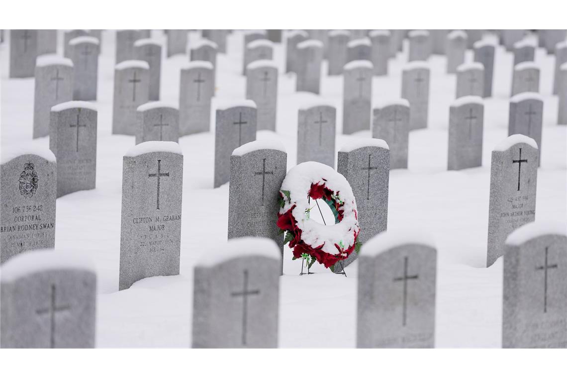 Ein schneebedeckter Kranz lehnt an einem Grabstein vor der Gedenkfeier zum Remembrance Day auf dem nationalen Soldatenfriedhof in Beachwood in Ottawa in Kanada.