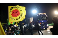 Ein Schwertransporter mit einem Castor-Behälter fährt an Teilnehmer einer Anti-Atomkraft-Demonstration vorbei.