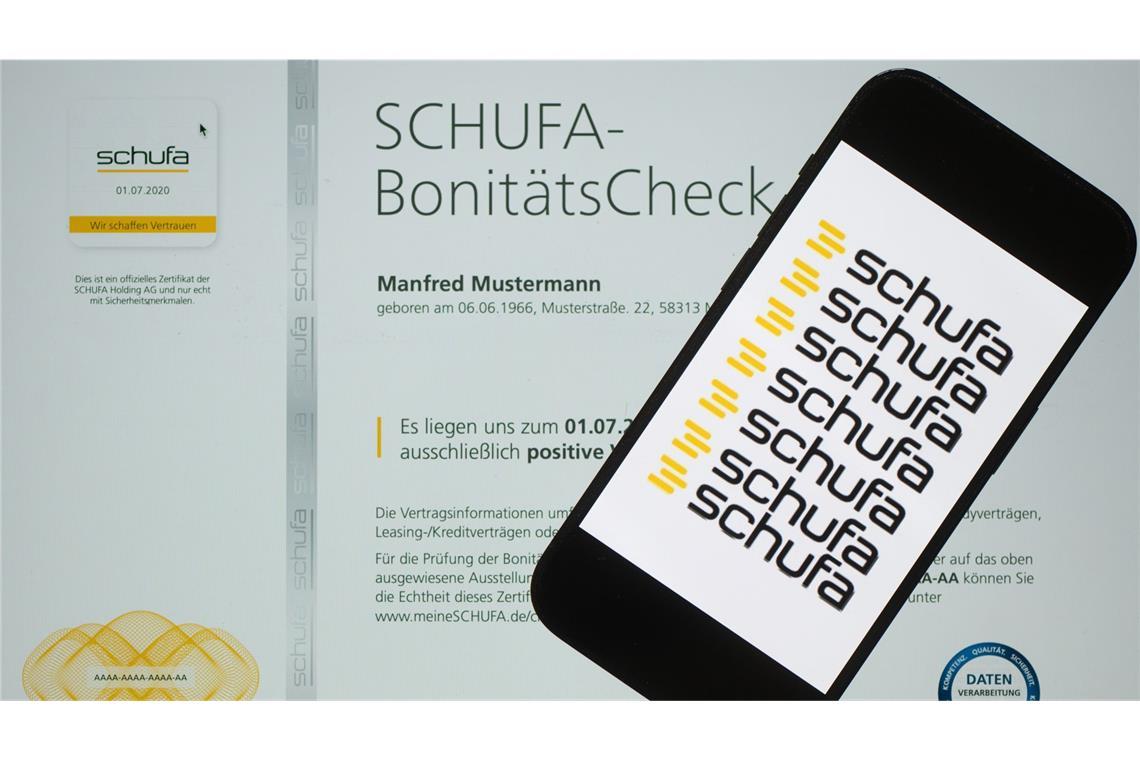 Ein Smartphone mit dem Logo der Wirtschaftsauskunftei Schufa liegt auf einem Display mit einem Musterdokument eines Schufa-Bonitätszertifikat.