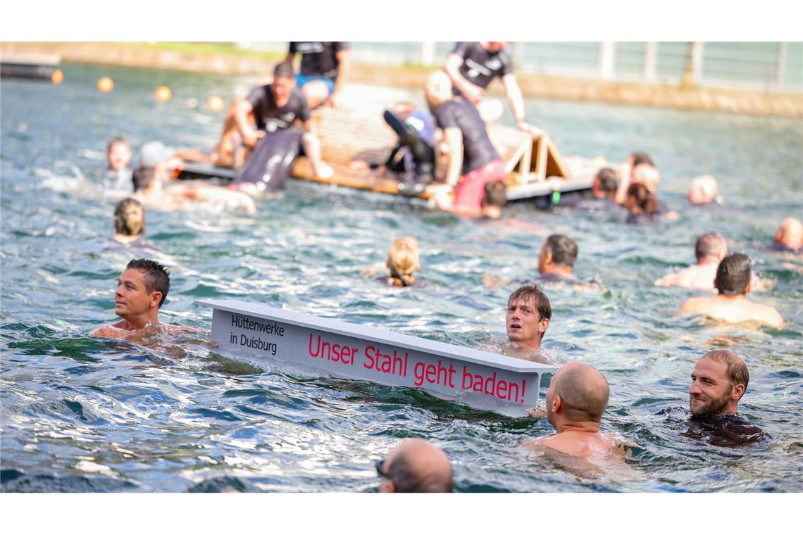 Ein symbolischer Stahlträger mit dem Slogan der Demo schwimmt im Duisburger Innenhafen zwischen zahlreichen Stahlbeschäftigten.