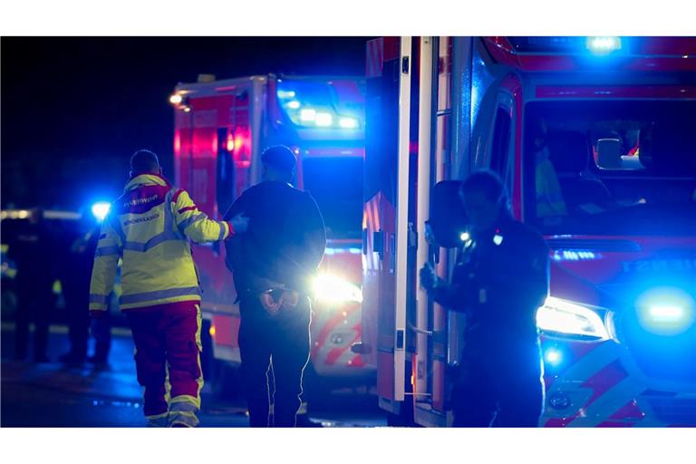 Ein Tatverdächtiger in Handschellen wird nach Schüssen in Mönchengladbach von einem Sanitäter zu einem Rettungswagen gebracht.