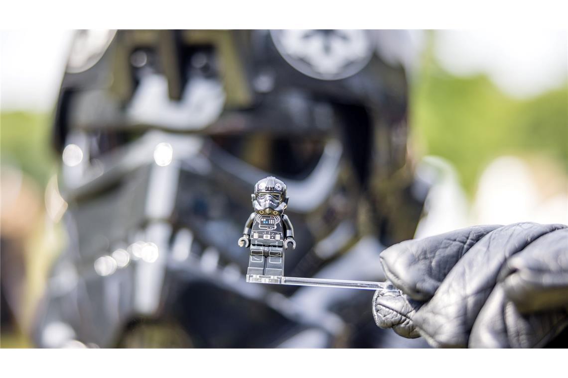 Ein Teilnehmer des Elbenwald Festivals, als Mitglied der Stormtroopers verkleidet, hält eine Figur seiner Rolle vor seinen Kopf.