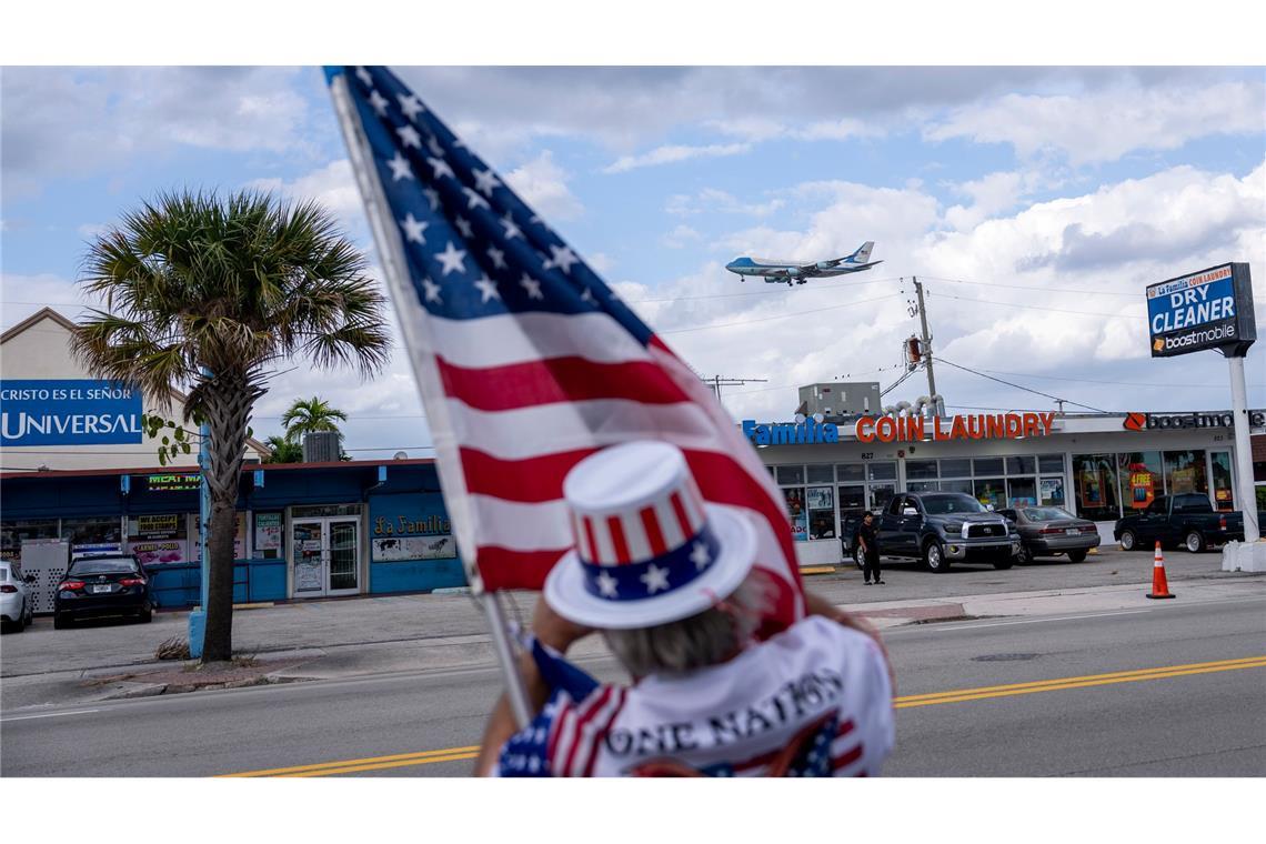 Bilder des Tages Ein Unterstützer hält eine US-Flagge und beobachtet, wie die Air Force One mit US-Präsident Trump an Bord auf dem Palm Beach International Airport landet.