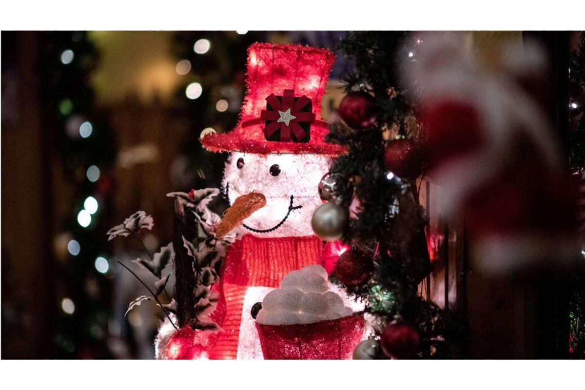 Wann schmückt man für Weihnachten? Ein von innen beleuchteter Deko-Schneemann steht im Flur der weihnachtlich dekorierten Wohnung