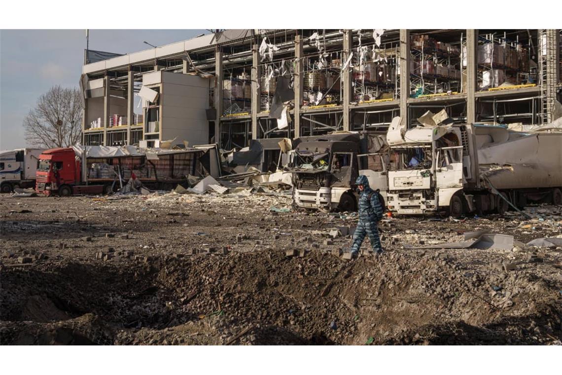 Ein Wachmann betrachtet einen Krater vor einem Novus-Logistikzentrum, das bei einem russischen Angriff auf Kiew beschädigt wurde (Archivbild).
