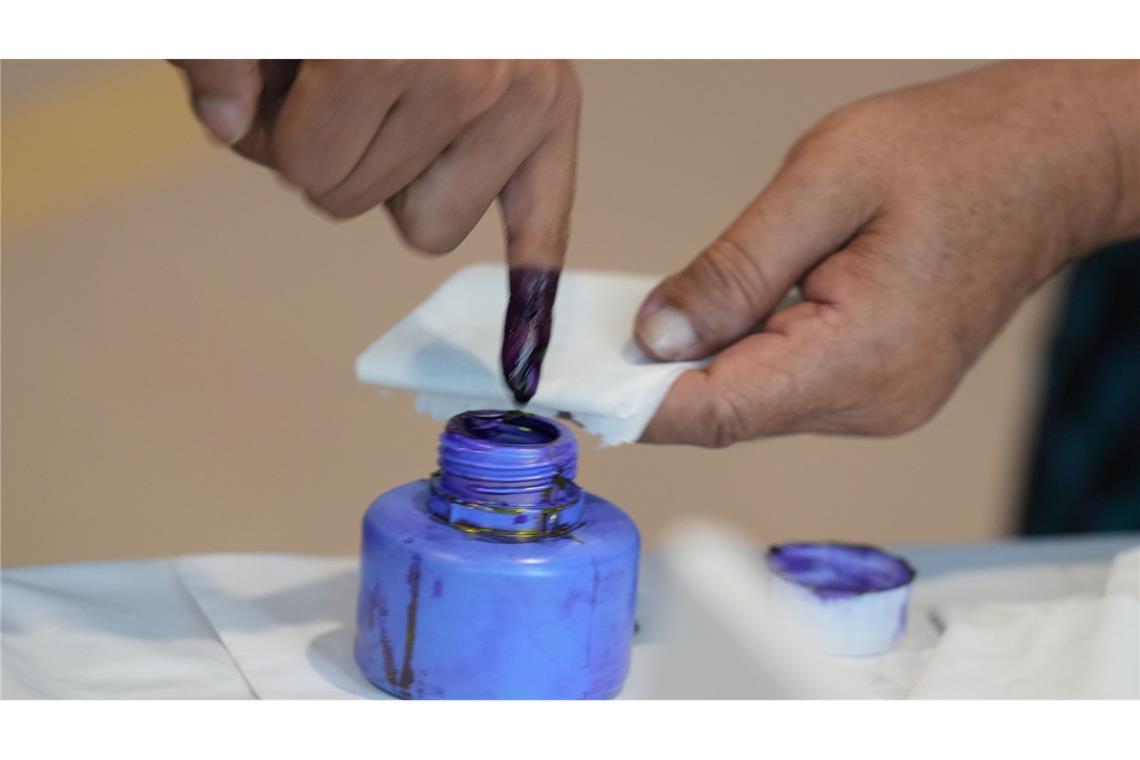 Ein Wähler taucht seinen Finger in ein Tintenfass.