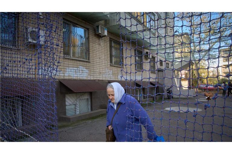 Eine Anwohnerin geht durch einem mit einem Anti-FPV-Drohnennetz bedeckten Hof in der Frontstadt Cherson in der Südukraine.