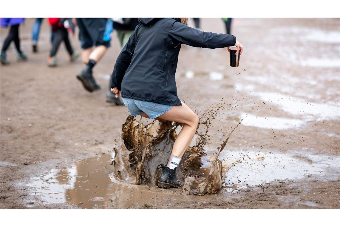 Eine Besucherin des Open-Air-Festivals "Rock im Park" springt in eine Pfütze.
