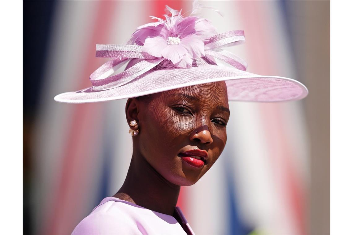 Eine Besucherin von Royal Ascot trägt einen zartrosa Tellerhut mit breiter Krempe, Schleifenband und Blütendetail. Der transparente Stoff wirft feine Schatten auf das Gesicht und verleiht dem Ton-in-Ton-Look eine elegante, sommerliche Wirkung.