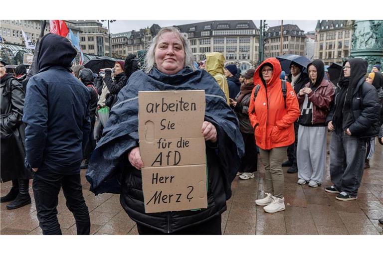 Eine Demonstrantin in Hamburg stellt auf einem Pappschild eine Frage an Bundeskanzler Friedrich Merz (CDU).