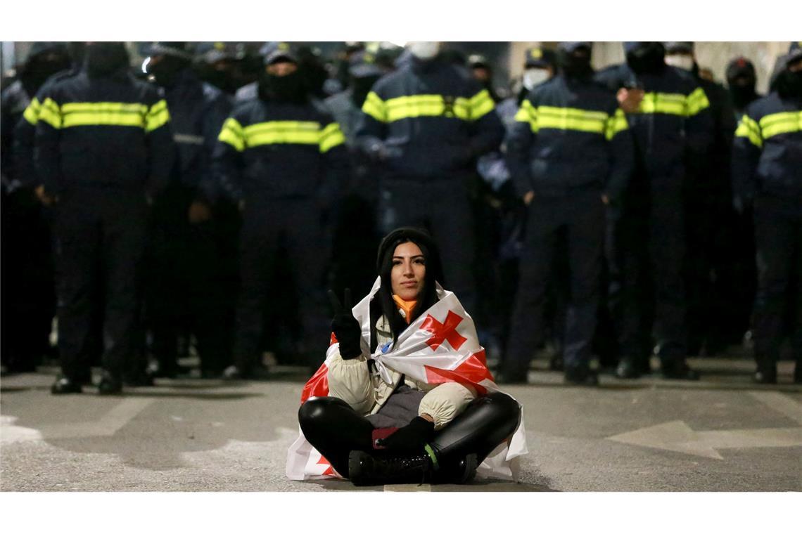 Bilder des Tages Eine Demonstrantin sitzt während der Proteste in Georgien vor Polizisten.