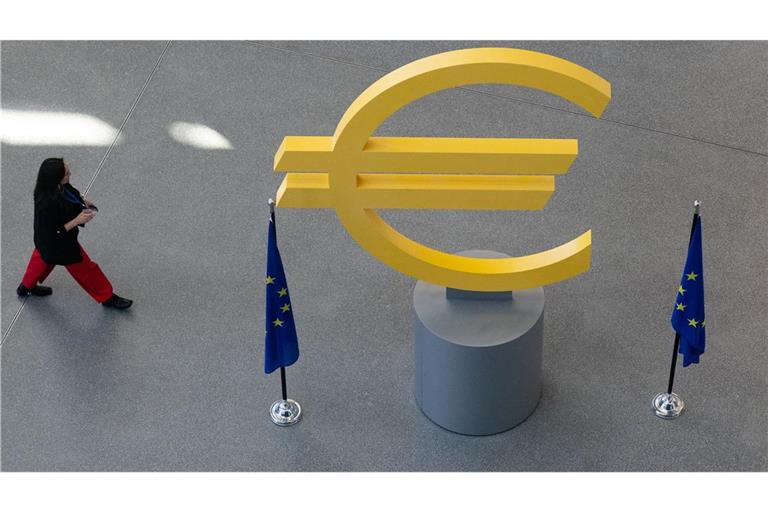 Eine Frau geht an einer Skulptur vorbei, die das Euro-Symbol in der Zentrale der Europäischen Zentralbank (EZB) darstellt. (zu dpa: «EZB stemmt sich mit höheren Zinsen gegen Inflationsschub»)