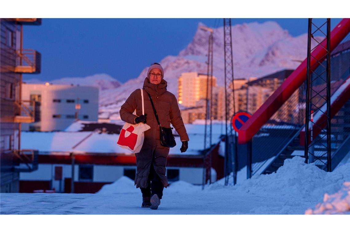 Eine Frau geht bei Sonnenuntergang auf einer Straße in Nuuk.