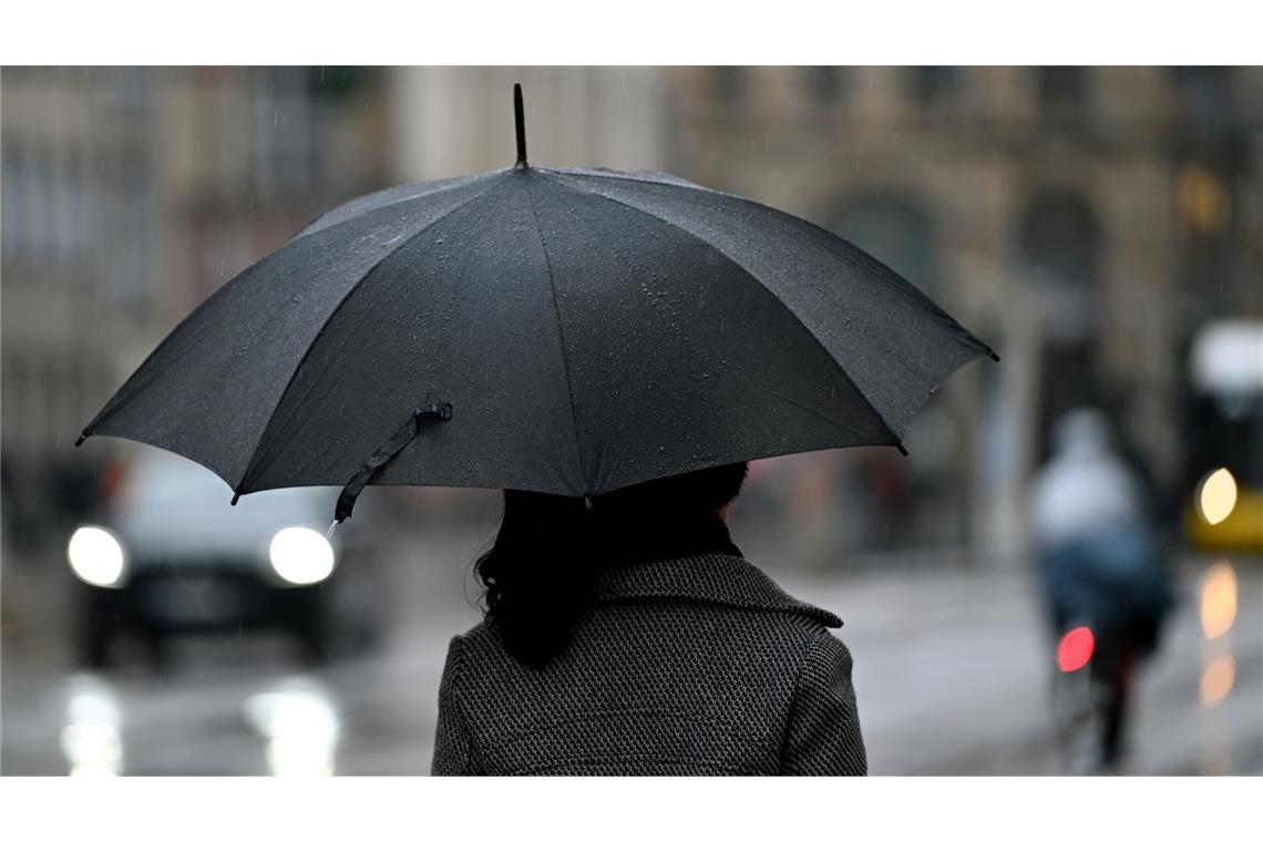 Bilder des Tages Eine Frau geht mit einem Regenschirm durch Berlin Mitte.