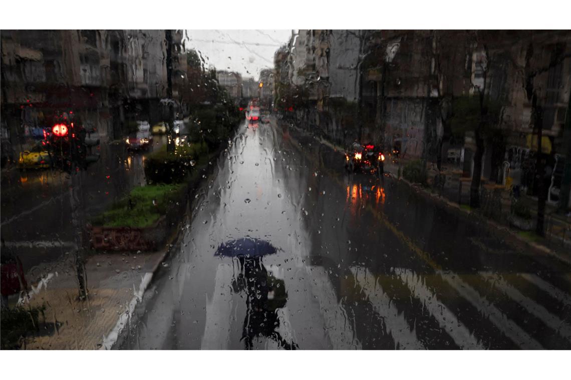 Bilder des Tages Eine Frau mit Regenschirm überquert eine Straße in Athen.