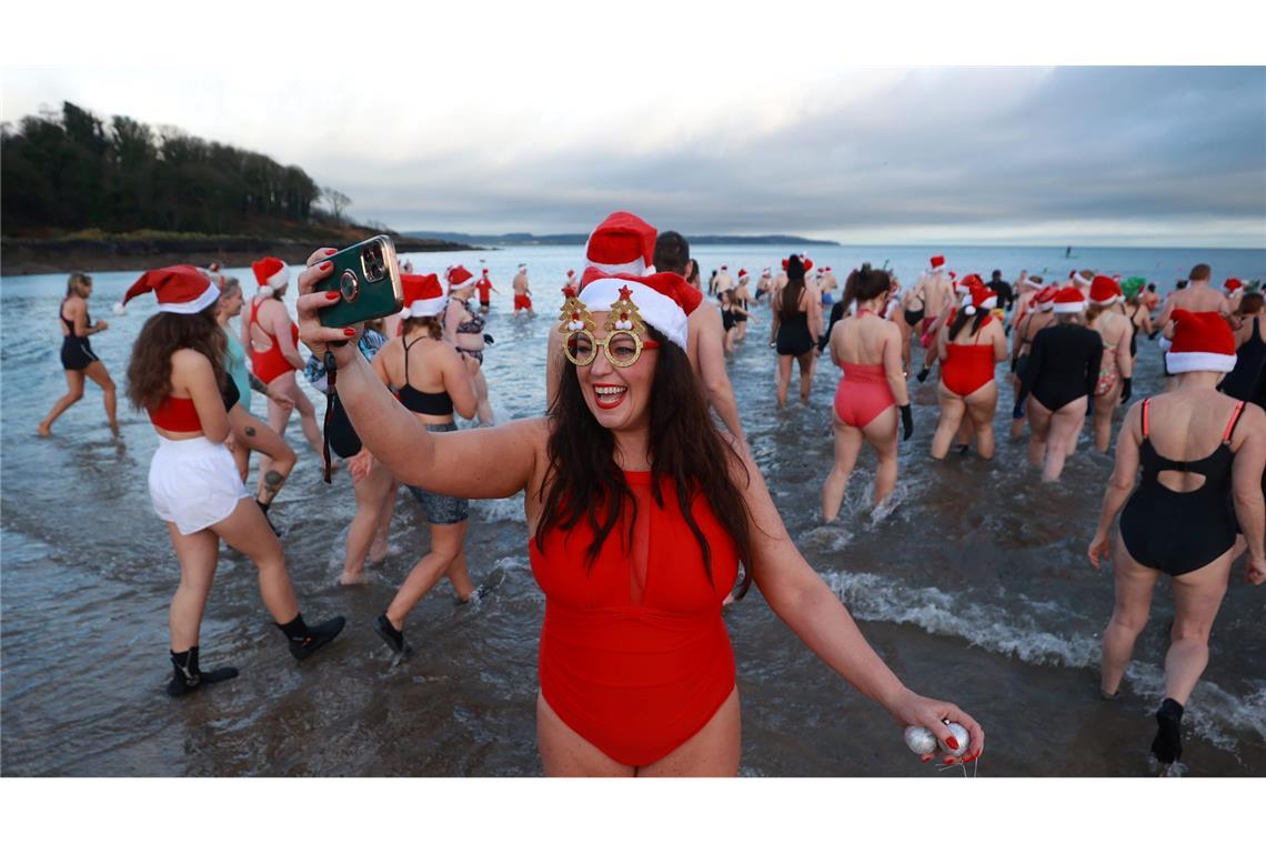 Bilder des Tages Eine Frau nimmt am jährlichen Weihnachtsschwimmen zu Heiligabend in Helen's Bay in Großbritannien teil und macht ein Selfie.