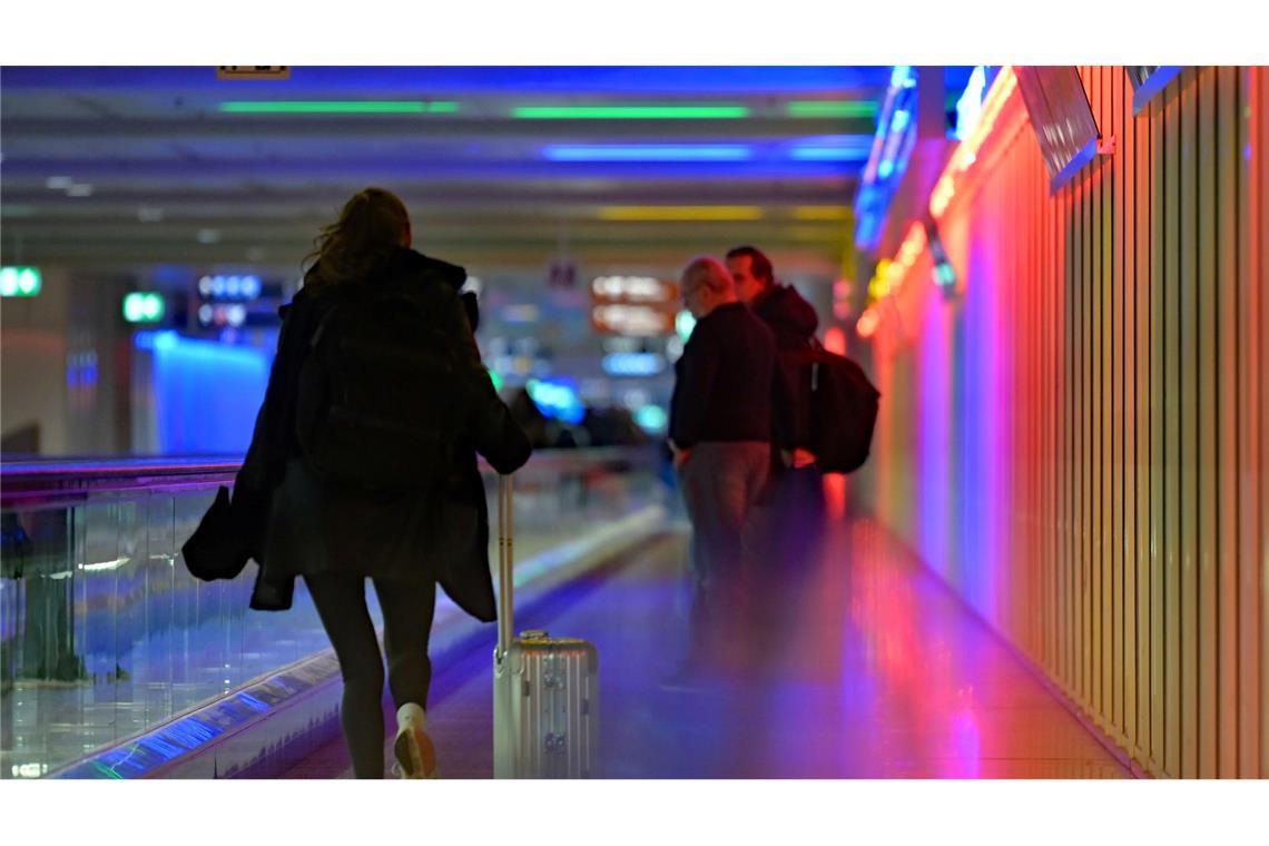 Eine Frau rennt mit ihrem Koffer neben einem Rollsteig am Flughafen. Heute ist der letzte Schultag vor den Herbstferien in Bayern.