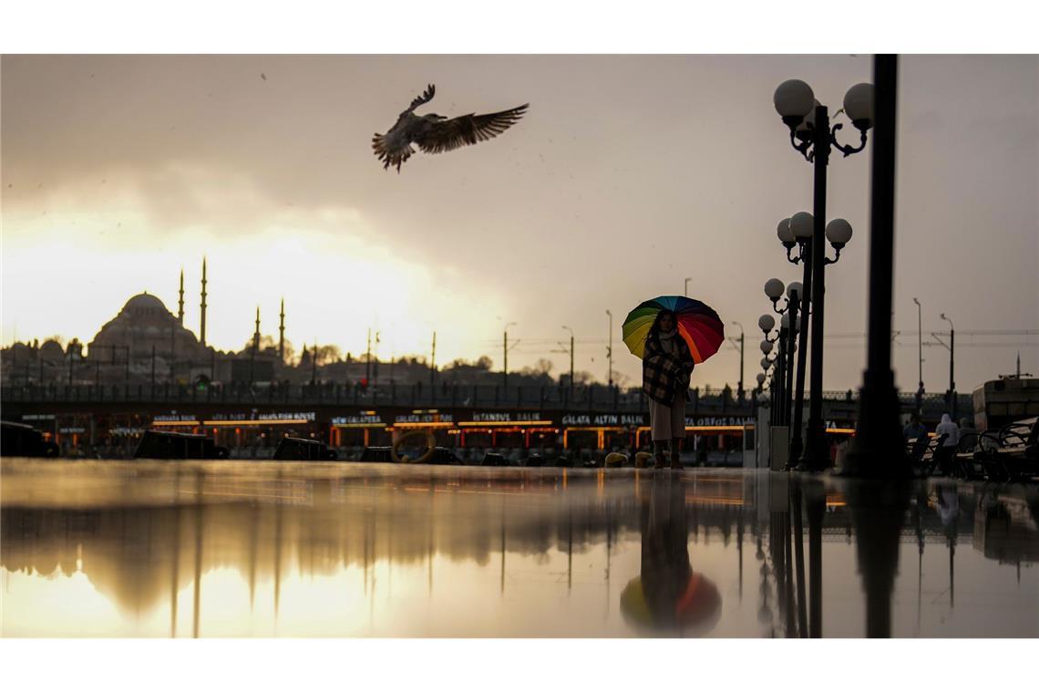 Bilder des Tages Eine Frau schützt sich mit einem Regenschirm vor leichtem Schneefall an der Strandpromenade von Karakoy.